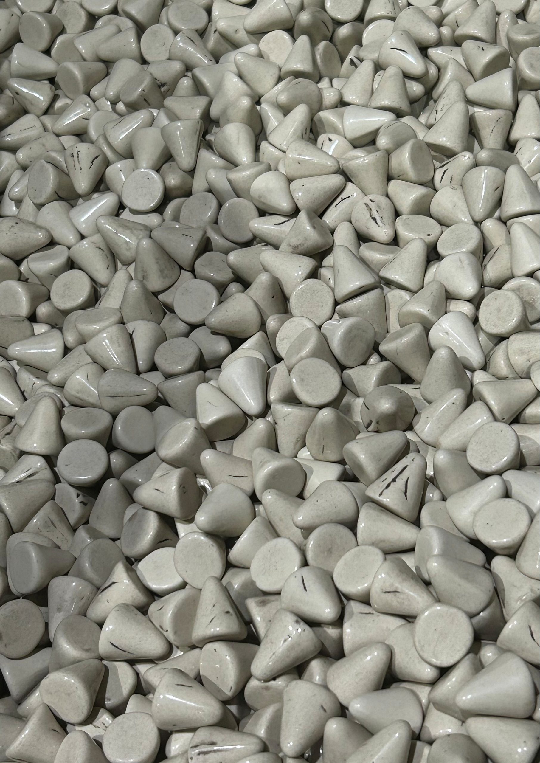 A close-up view of many small, smooth, white ceramic cones and cylinders packed together, creating a textured and repetitive pattern.