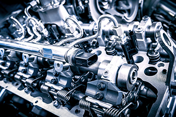 Close-up view of a complex mechanical assembly, showing metallic parts, pipes, valves, and components of an internal combustion engine. The image highlights intricate engine details and engineering.