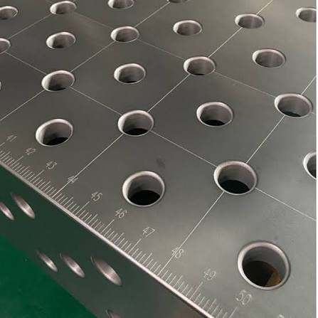 A metal workbench with evenly spaced circular holes and engraved measurement markings, used for precision tasks in workshops or manufacturing settings.